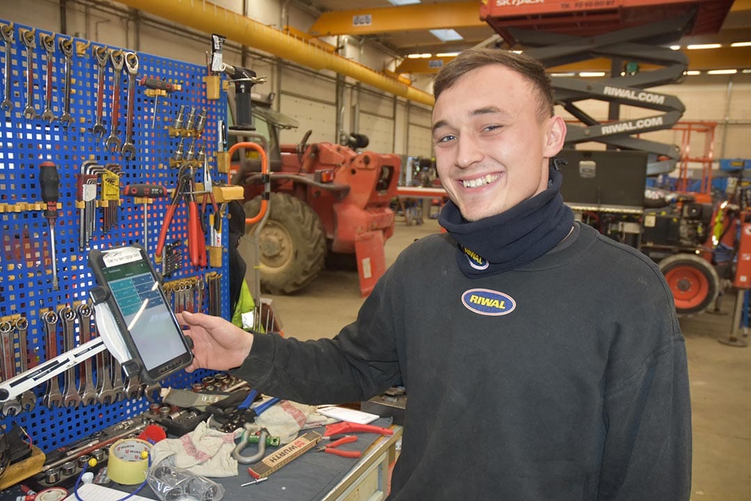 Bild einer Werkstatt, in der eine lächelnde Person ein Terminal drückt