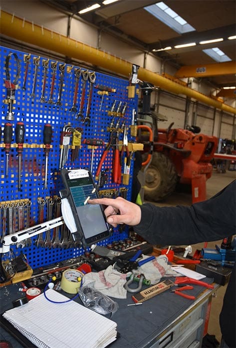 Bild einer Werkstatt, in der eine Person auf ein Terminal drückt