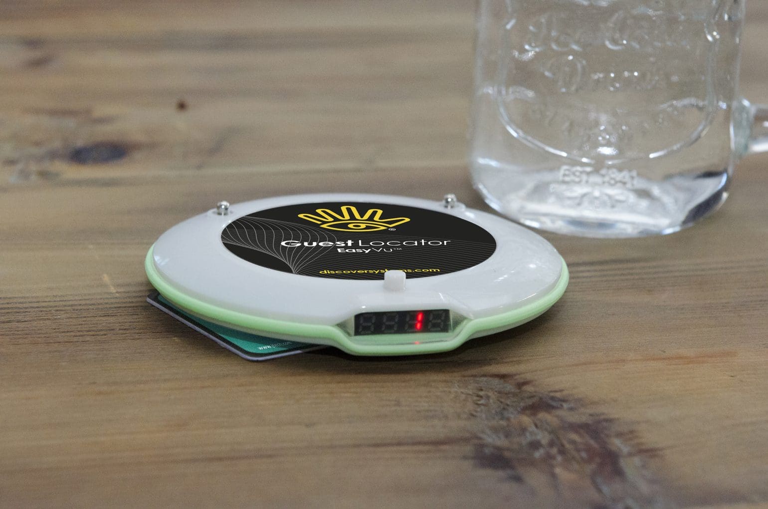 Ein JTECH EasyVu - Gästestandort, der auf einem neben einem Glas liegt