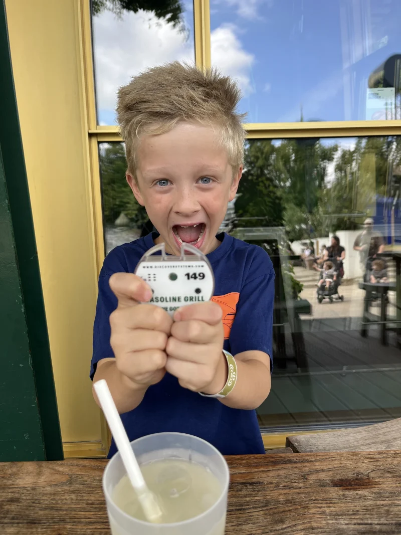 Ein fröhlicher Junge hält einen Pager in der Hand und wartet gespannt auf seine Pommes